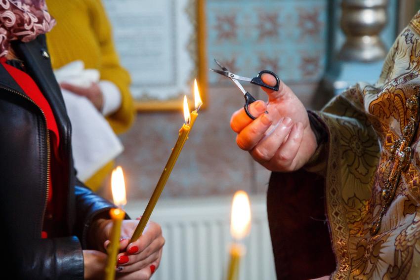 Burning candle in the hands of the newlyweds